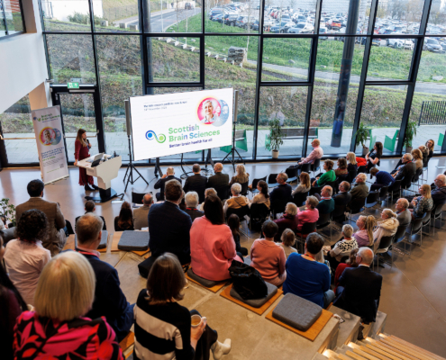 An audience of people are sitting watching a presentation