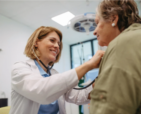 Smiling doctor with is checking an elderly female patient with stethascope