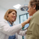 Smiling doctor with is checking an elderly female patient with stethascope