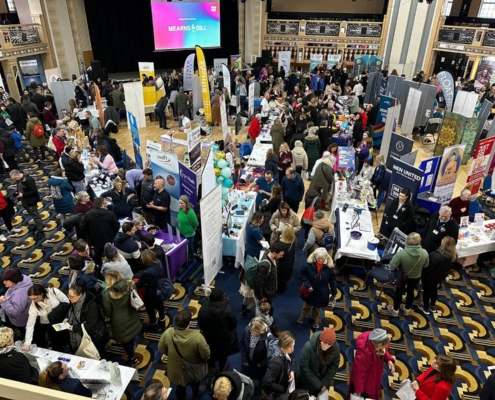 Lots of people milling around stands in a large room