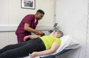 ScottishBrainSciences_clinical team Edinburgh A woman is lying on a clinical bed having her blood pressure taken by a male nurse