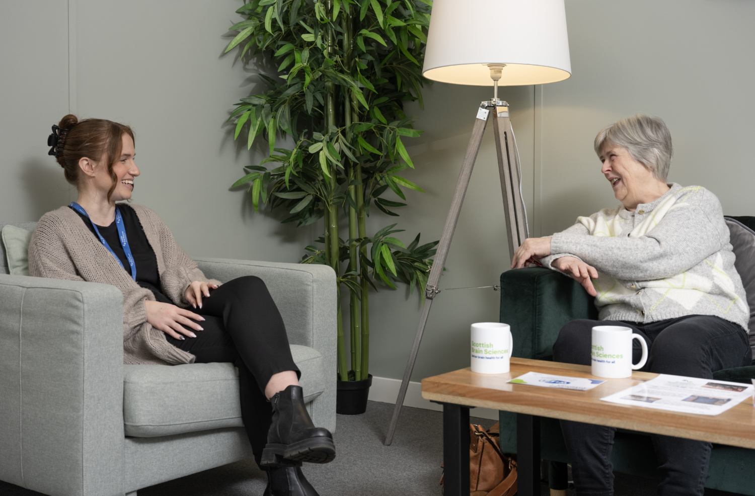 Two women sitting on sofas smiling and talking to each other