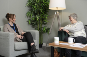 Two women sitting on sofas smiling and talking to each other