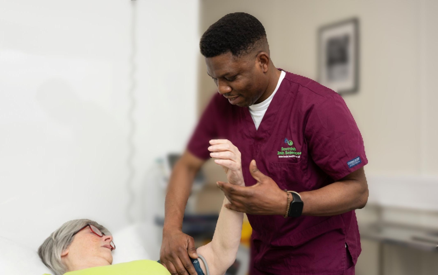 Male nurse checking blood pressure of female patient who is lying on a bed