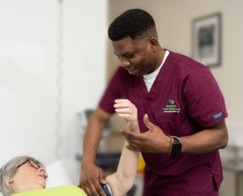 Male nurse checking blood pressure of female patient who is lying on a bed