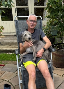 A man sitting in a garden chair with a dog on his lap