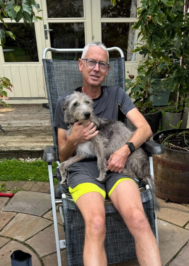 A man sitting in a garden chair with a dog on his lap