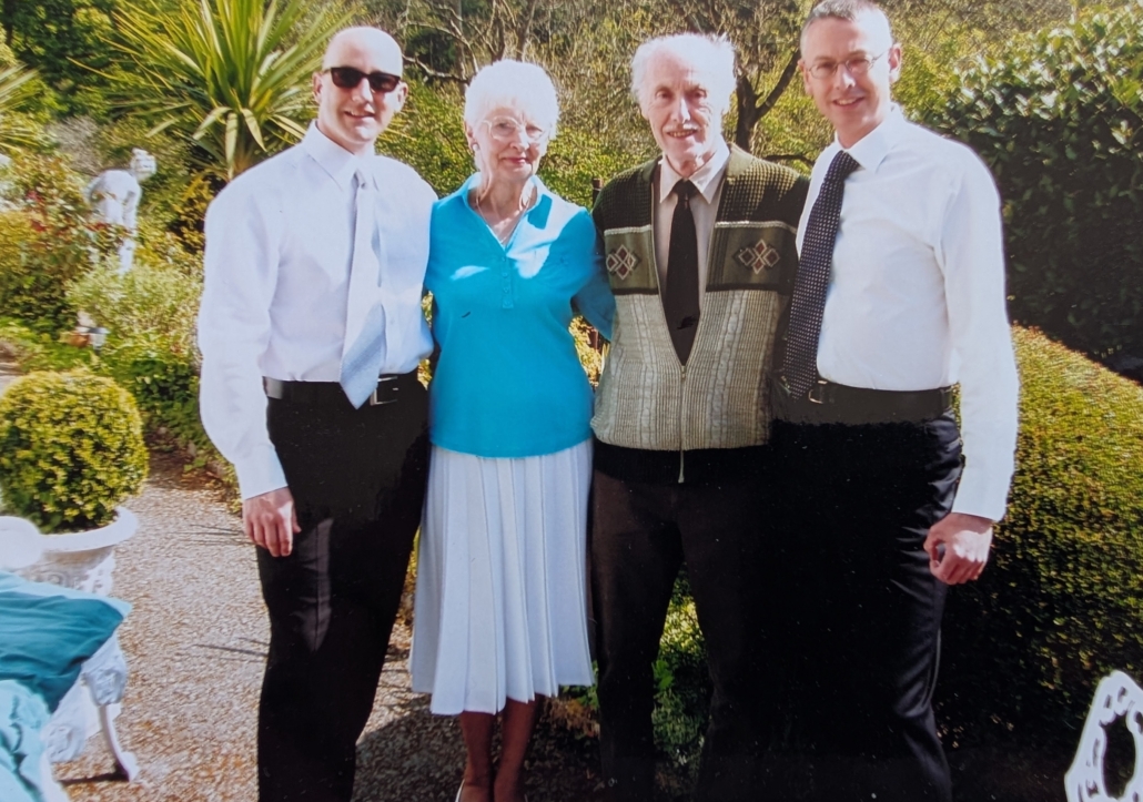 A woman and three men standing side by side smiling at the camera