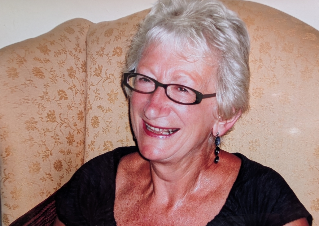 A woman with white hair and glasses smiling
